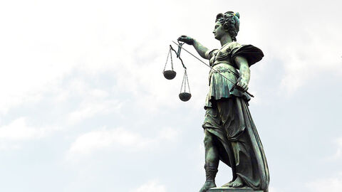 Justitia Justitia Statue vor einem hellen Himmel.